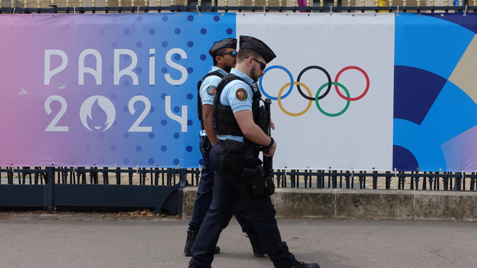 French police patrol in front of the Assemblée Nationale passing an advertising poster of the Paris 2024 Olympic Games. (Reuters Photo)  