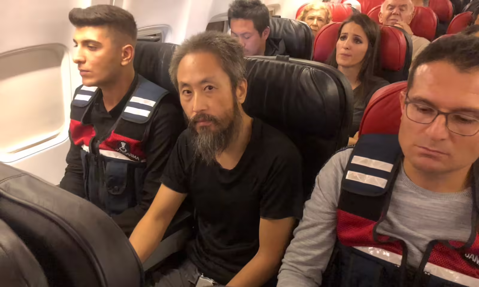 Japanese journalist Jumpei Yasuda sits between two Turkish gendarmes on a flight to Istanbul after his release from captivity. (Photo via Reuters)