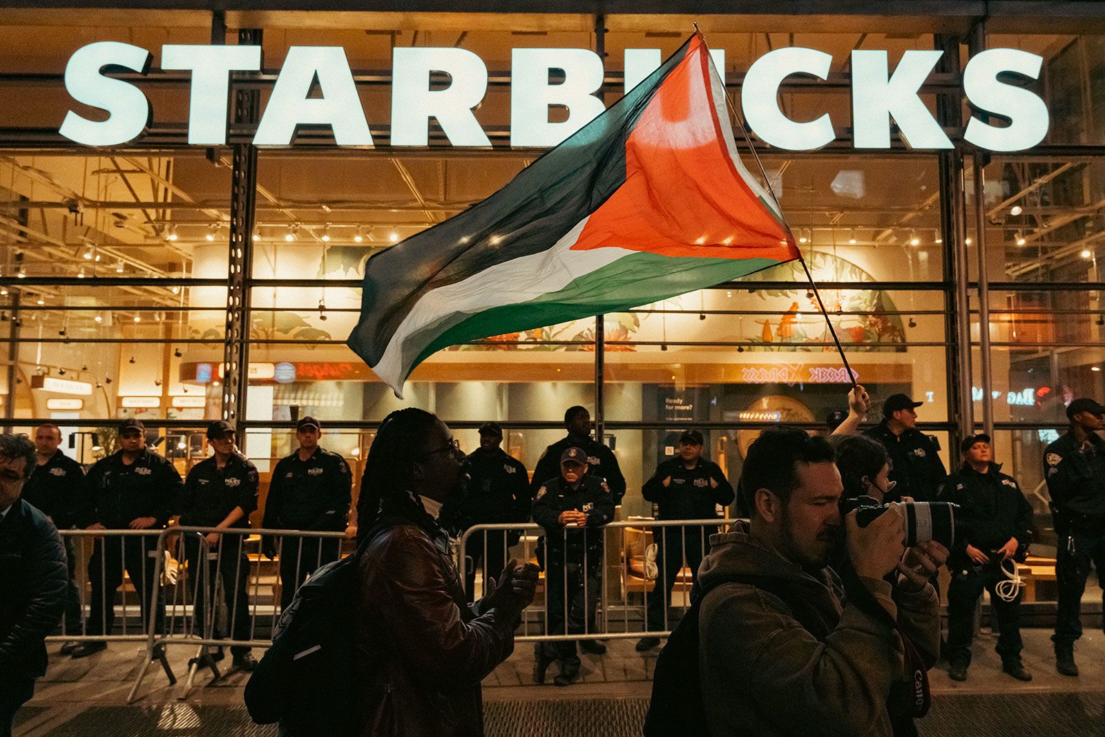 Police officers are seen barricading a Starbucks retail store from thousands of demonstrators supporting Palestine in New York City December 21, 2023 (AP Photo)