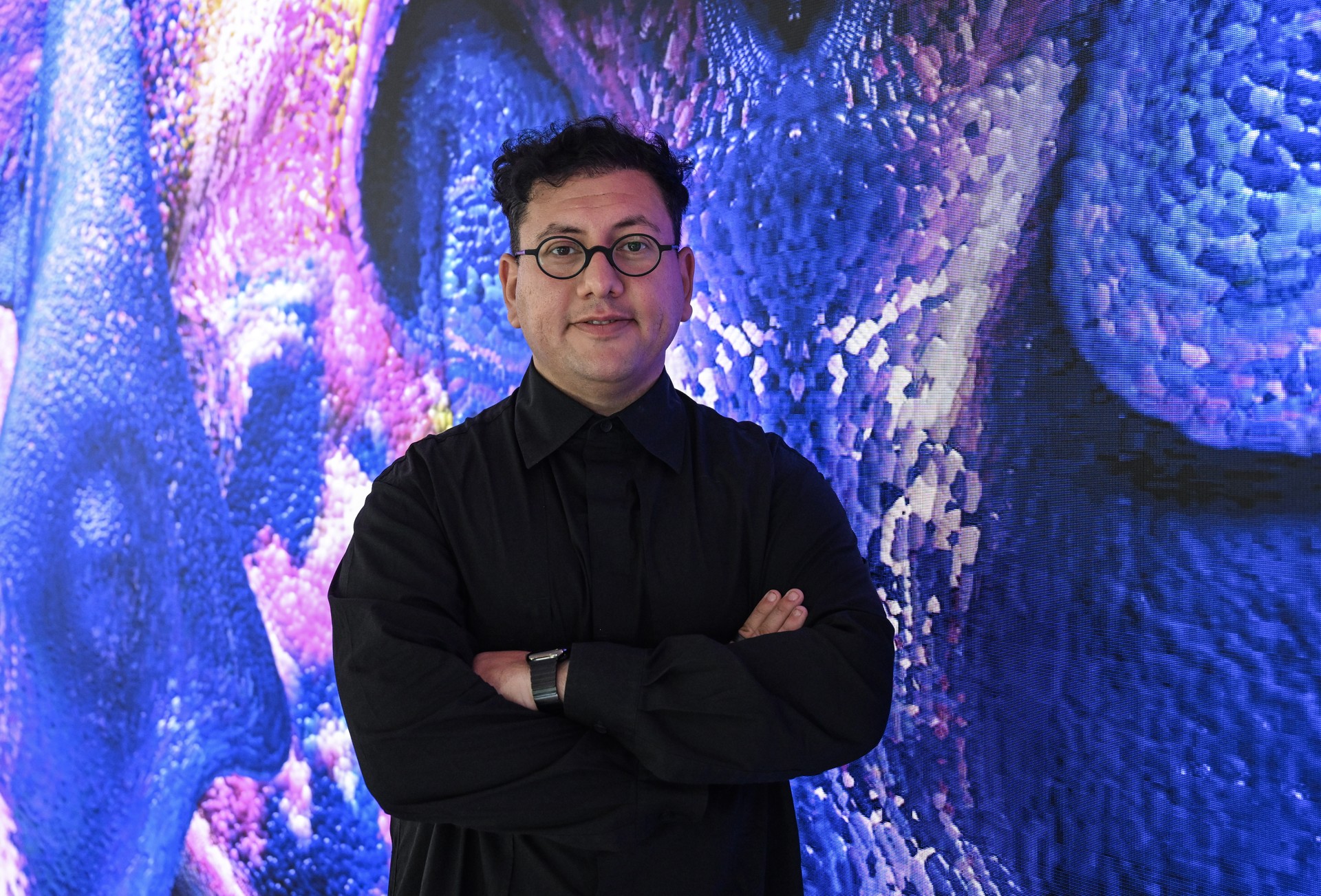 Turkish media artist Refik Anadol poses in front of his AI-powered digital artwork at the United Nations headquarters in New York, United States, September 21, 2024. (AA Photo)