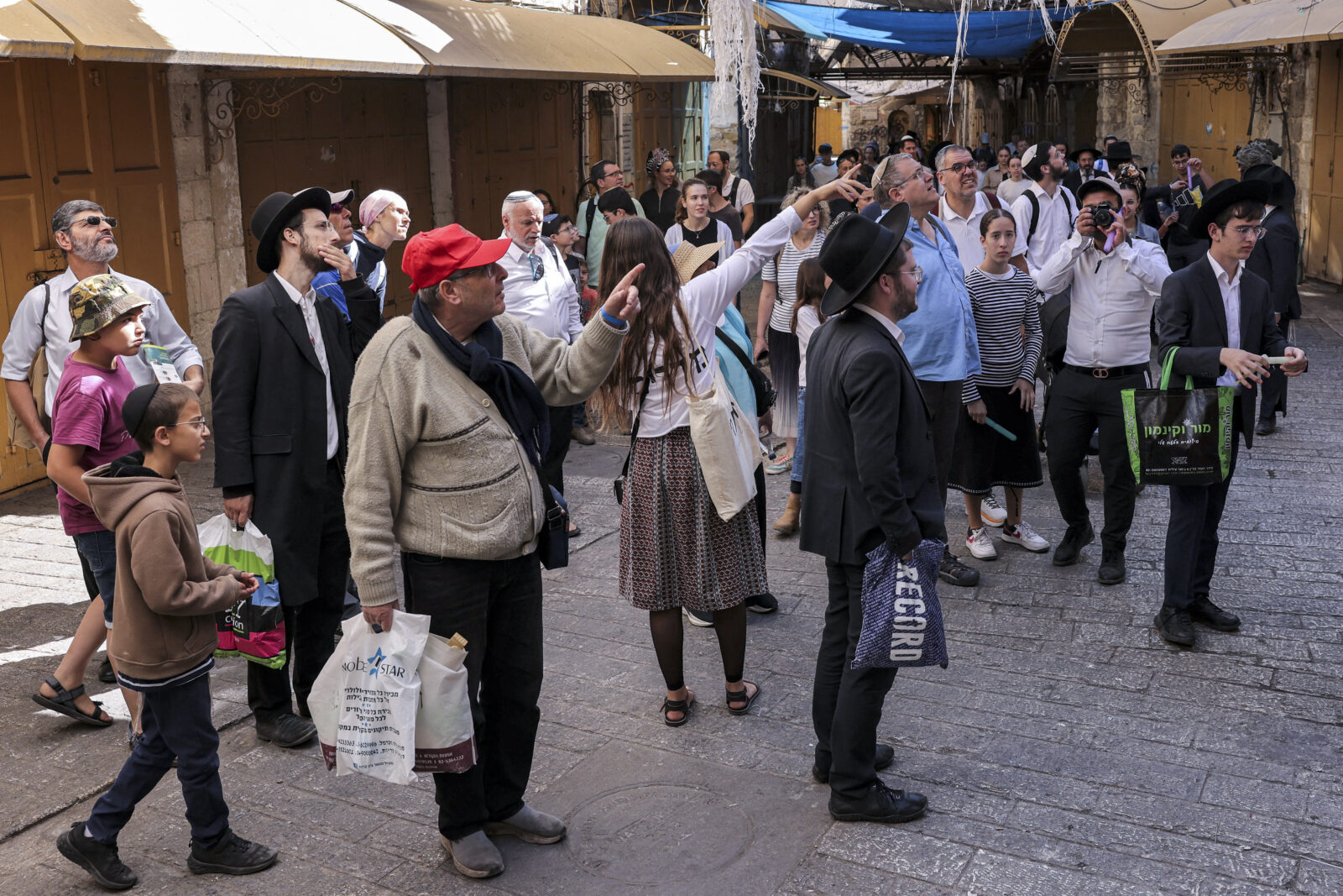 Israeli settlers gesture toward a building during an escorted tour of the market in the Palestinian part of the old city of Hebron in the occupied West Bank on Oct. 22, 2024. (AFP Photo)