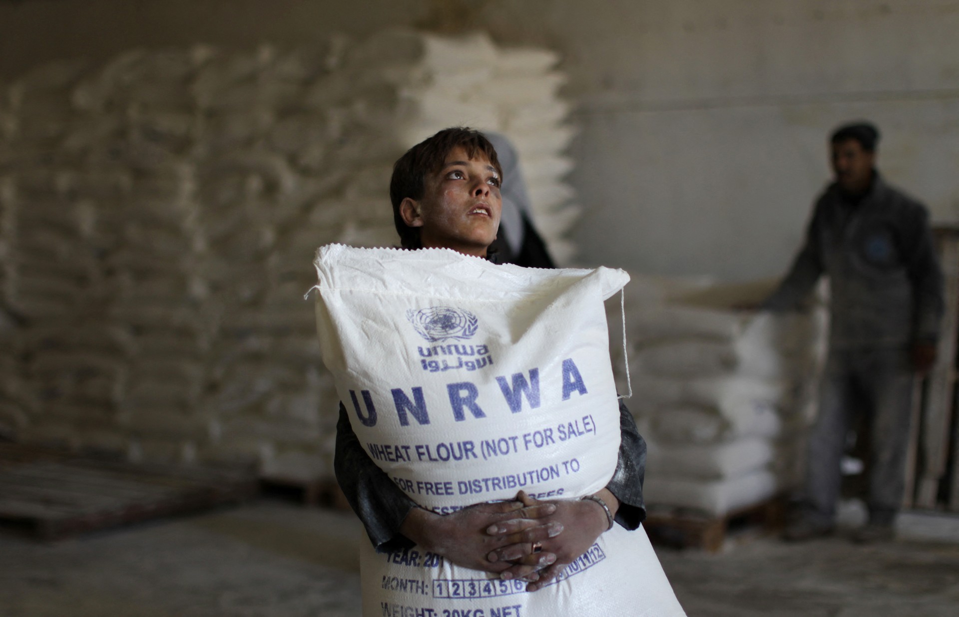 A Palestinian boy holds a sack of flour at a United Nations Relief and Works Agency (UNRWA) aid distribution centre in Gaza City on April 10, 2013. The United Nations reopened aid distribution centres in Gaza, after a four-day closure in response to the storming of its offices last week by protesters demanding reinstatement of a monthly cash allowance to poor families which was halted from April 1 due to budget cuts. AFP PHOTO/MAHMUD HAMS - Israel's parliament on October 29, 2024, banned the United Nations agency for Palestinian refugees (UNRWA) from operating in Israel and occupied east Jerusalem, despite objections from the international community. UNRWA chief Philippe Lazzarini condemned the decision, saying it set "a dangerous precedent". (Photo by Mahmud HAMS / AFP)