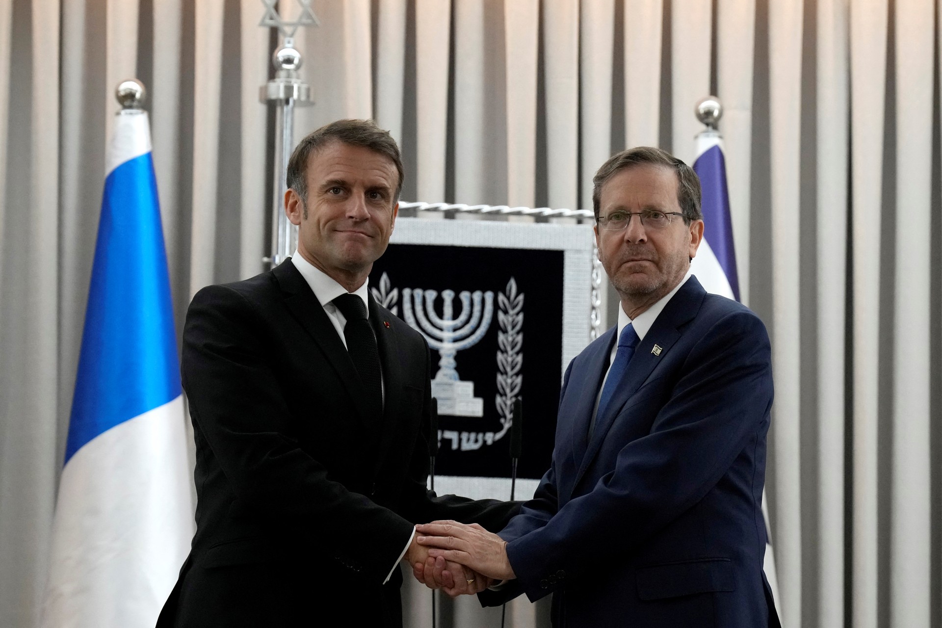French President Emmanuel Macron, left, shakes hands with Israel's President Isaac Herzog in Jerusalem, Tuesday, Oct. 24, 2023. Emmanuel Macron is traveling to Israel to show France's solidarity with the country and further work on the release of hostages who are being held in Gaza.      Christophe Ena/Pool via REUTERS