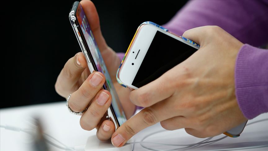 An individual holds two mobile phones. (AA Photo)
