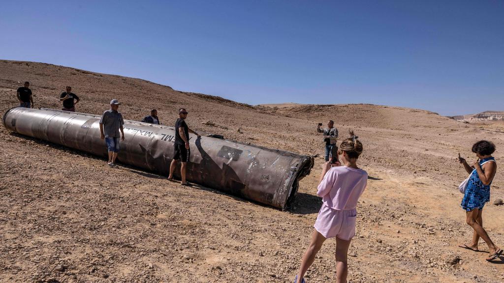 People take pictures near the remains of an Iranian missile in the Negev desert near Arad, Israel. (AFP Photo)
