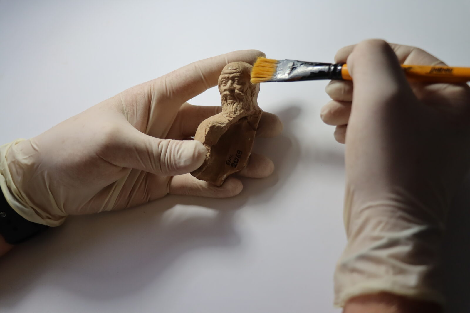 An archaeologist examines a figurine belonging to the Early Hellenistic Period, dating from 300 to 200 B.C., depicting ancient philosophers defined as 