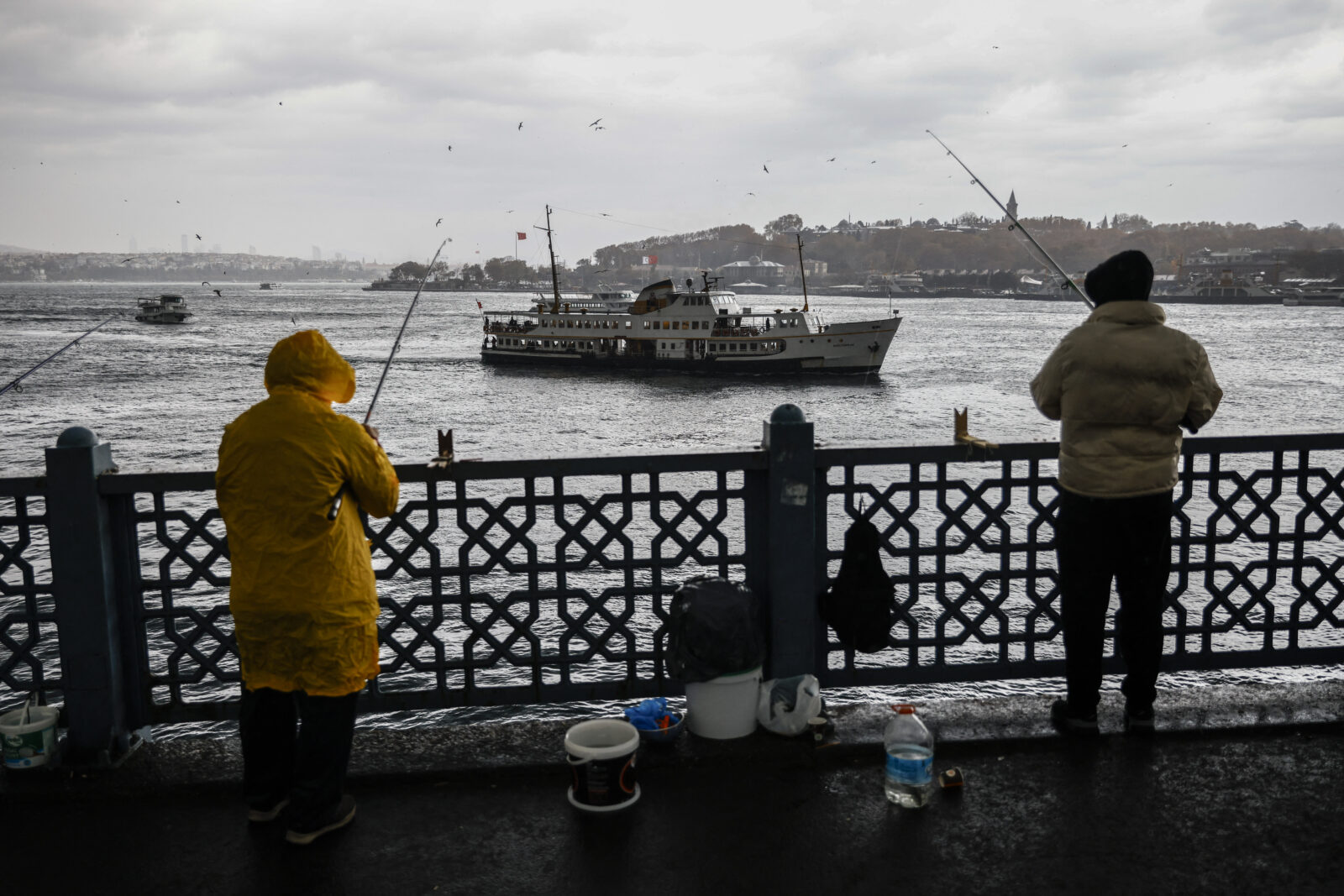 Türkiye's weather warnings: Fishermen fish on the Galata Bridge during heavy rain in Eminonu district of Istanbul on November 21, 2024. (AFP Photo)