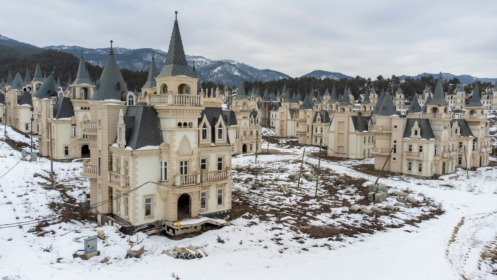 Snow-covered ground-level view of Burj Al Babas’ abandoned villas against a mountainous backdrop, Mudurnu, Bolu, Türkiye, Feb. 15, 2022. (Adobe Stock Photo)
