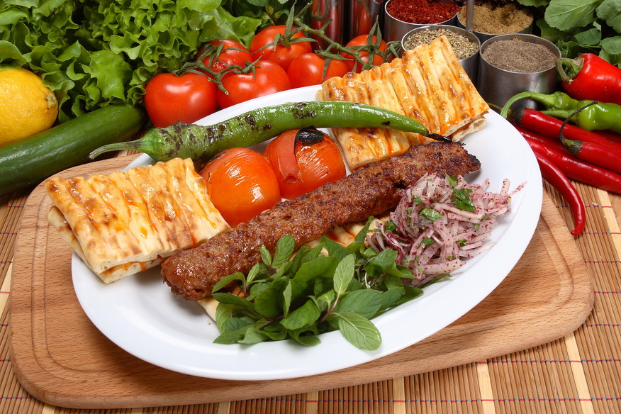A fiery, charcoal-grilled kebab made with spiced ground lamb, served with fresh herbs and vegetables. (Adobe Stock Photo)