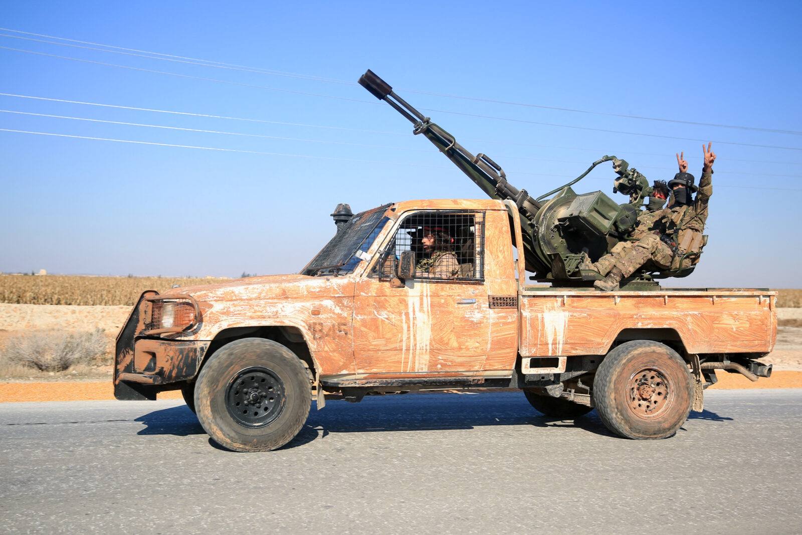 Anti-government fighters ride military vehicles as they drive along a road in the eastern part of Aleppo province on December 1, 2024. - Syria's second-largest city Aleppo has fallen from government control for the first time since the country's conflict began more than a decade ago, a war monitor said on December 1, after a surprise advance by rebels. (Photo by Aref TAMMAWI / AFP)<img src=
