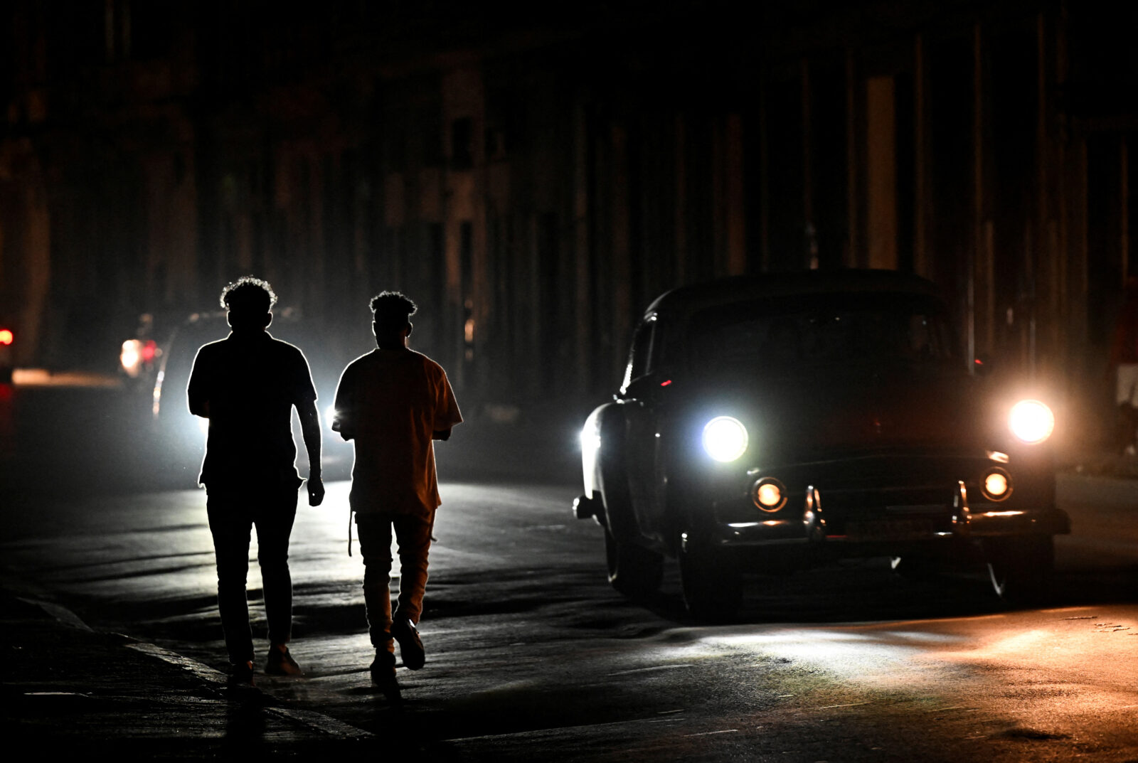 Cars ride on a street at night during a nationwide blackout caused by a grid failure in Havana on December 4, 2024. - Cash-strapped Cuba on Wednesday was struggling to revive its power grid, after fixing a failure at the country's largest power plant, which had caused yet another nationwide blackout. (Photo by ADALBERTO ROQUE / AFP)