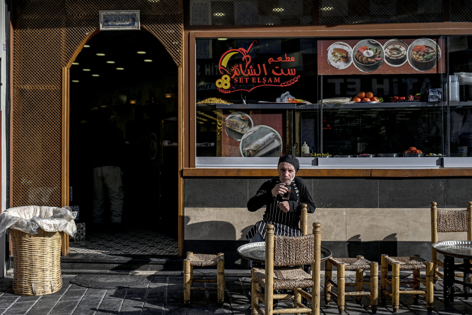A man sits in front of a Syrian restaurant at Malta bazaar, with other mainly Syrian shopkeepers at Fatih district in Istanbul, on December 6, 2024. (Photo by Ozan KOSE / AFP)