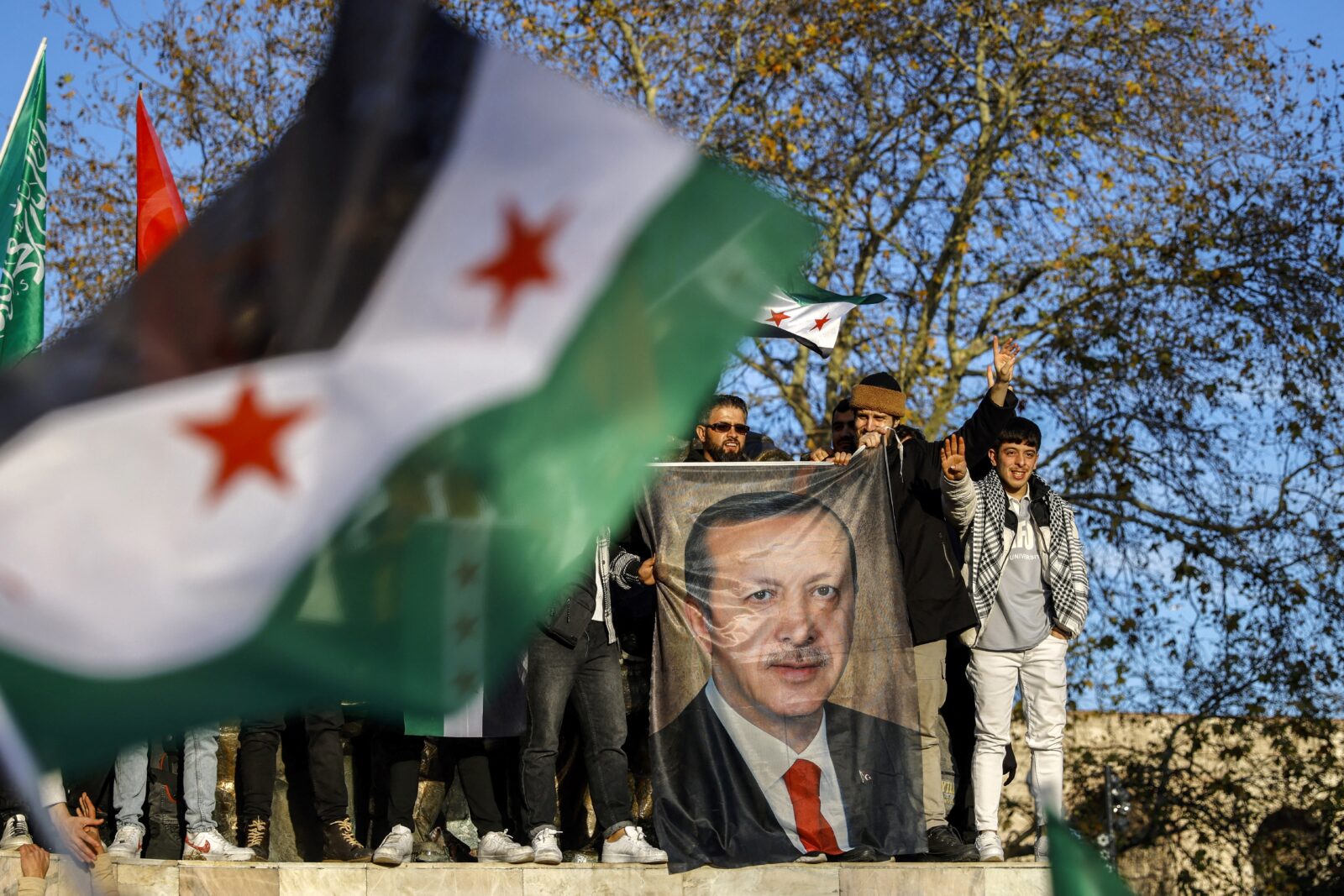 People hold a banner featuring Turkish President Recep Tayyip Erdogan as members of the Syrian community and supporters gather to celebrate the fall of Syrian president Bashar al-Assad in the face of an offensive by Islamist-led rebels, in Istanbul's Fatih district on December 8, 2024. - Islamist-led rebels toppled Syria's longtime ruler Bashar al-Assad in a lightning offensive that a UN envoy called