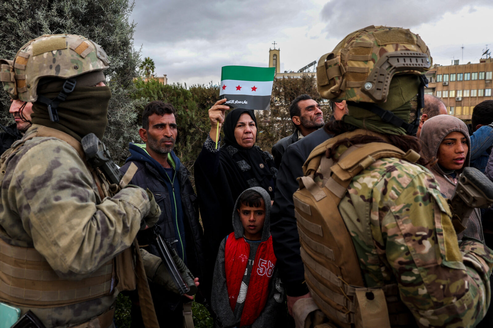 A woman waves a Syria flag during a parade by fighters affiliated with Syria's new administration in the capital Damascus, Dec. 27, 2024. (AFP Photo)