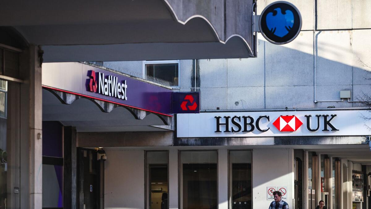 People walk pass a branches of HSBC, Natwest and Barclays banks on a pedestrianised shopping street in Bracknell town centre. (AFP Photo)