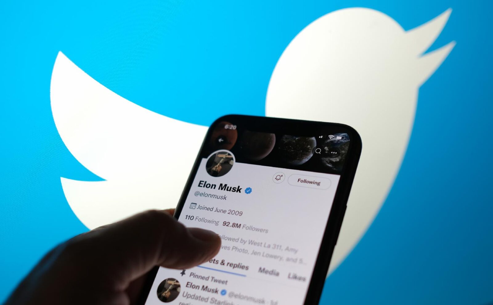 The file photo shows a smartphone displaying Elon Musk's Twitter profile, held in front of the Twitter logo in the background. (AFP Photo)