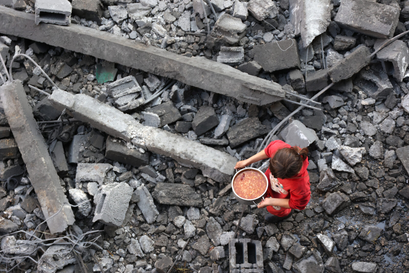 EDITORS NOTE: Graphic content / A Palestinian girl carries a portion of food as she makes her way amidst the debris at the site of an Israeli strike the previous night, in Jabalia, in the central Gaza Strip on January 1, 2025, as the war between Israel and Hamas militants continues. (Photo by Omar AL-QATTAA / AFP)<img src=