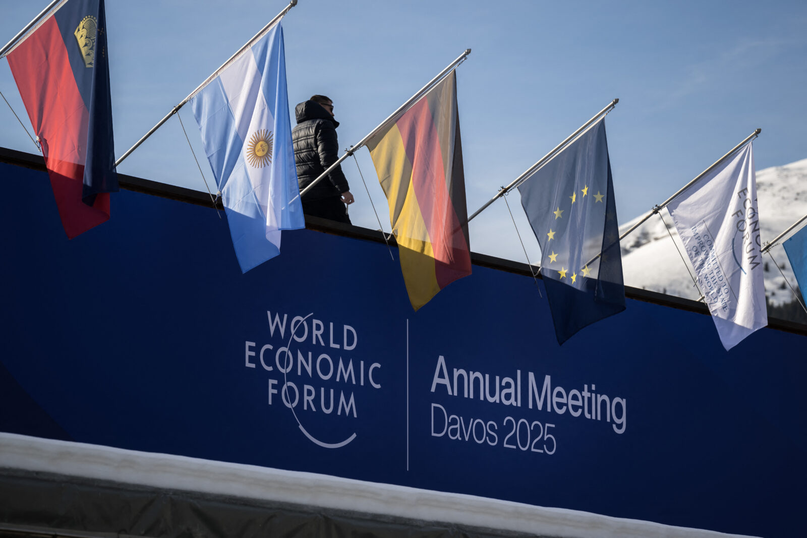 A staff walks to fix flags placed atop the Congress Center during the World Economic Forum (WEF) annual meeting in the Alpine resort of Davos in Switzerland, on Jan. 20, 2025. (AFP Photo)
