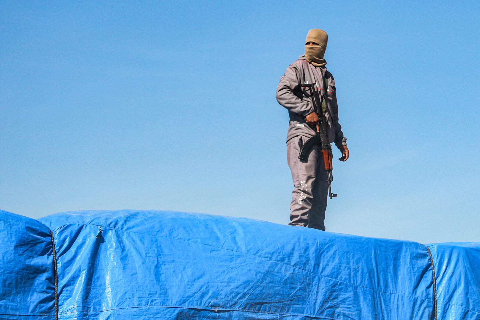 A member of security forces loyal to Hamas stands guard atop one of the trucks carrying humanitarian aid coming in from the Kerem Shalom border crossing (also known as Karem Abu Salem) and arriving in al-Shoka, east of Rafah in the southern Gaza Strip on January 21, 2025. (AFP Photo)
