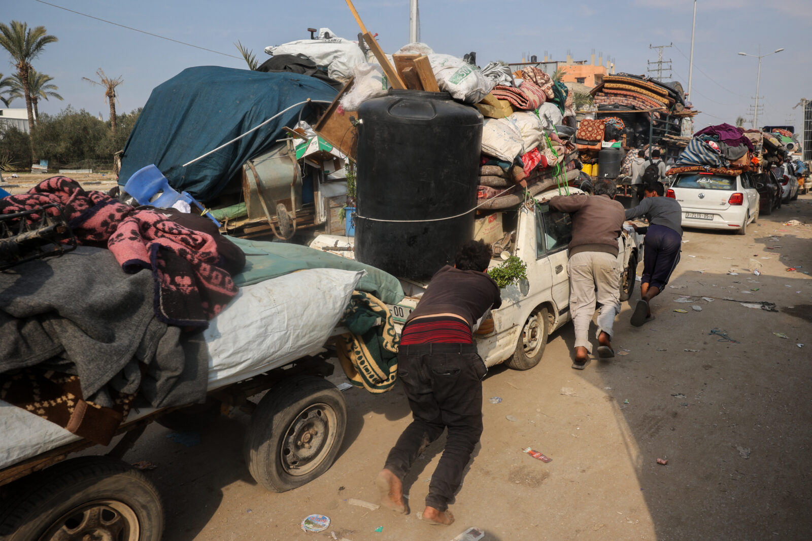 People push a car loaded with personal belongings along Salah al-Din road in Nuseirat as displaced Palestinians make their way to the northern part of the Gaza strip on January 28, 2025. (AFP Photo)