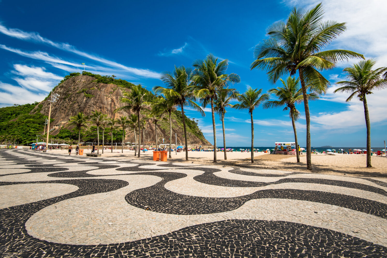 The famous black-and-white wave mosaics of Copacabana Beach, set against Rio de Janeiro’s lush hills and golden sand, Brazil. (Adobe Stock Photo)