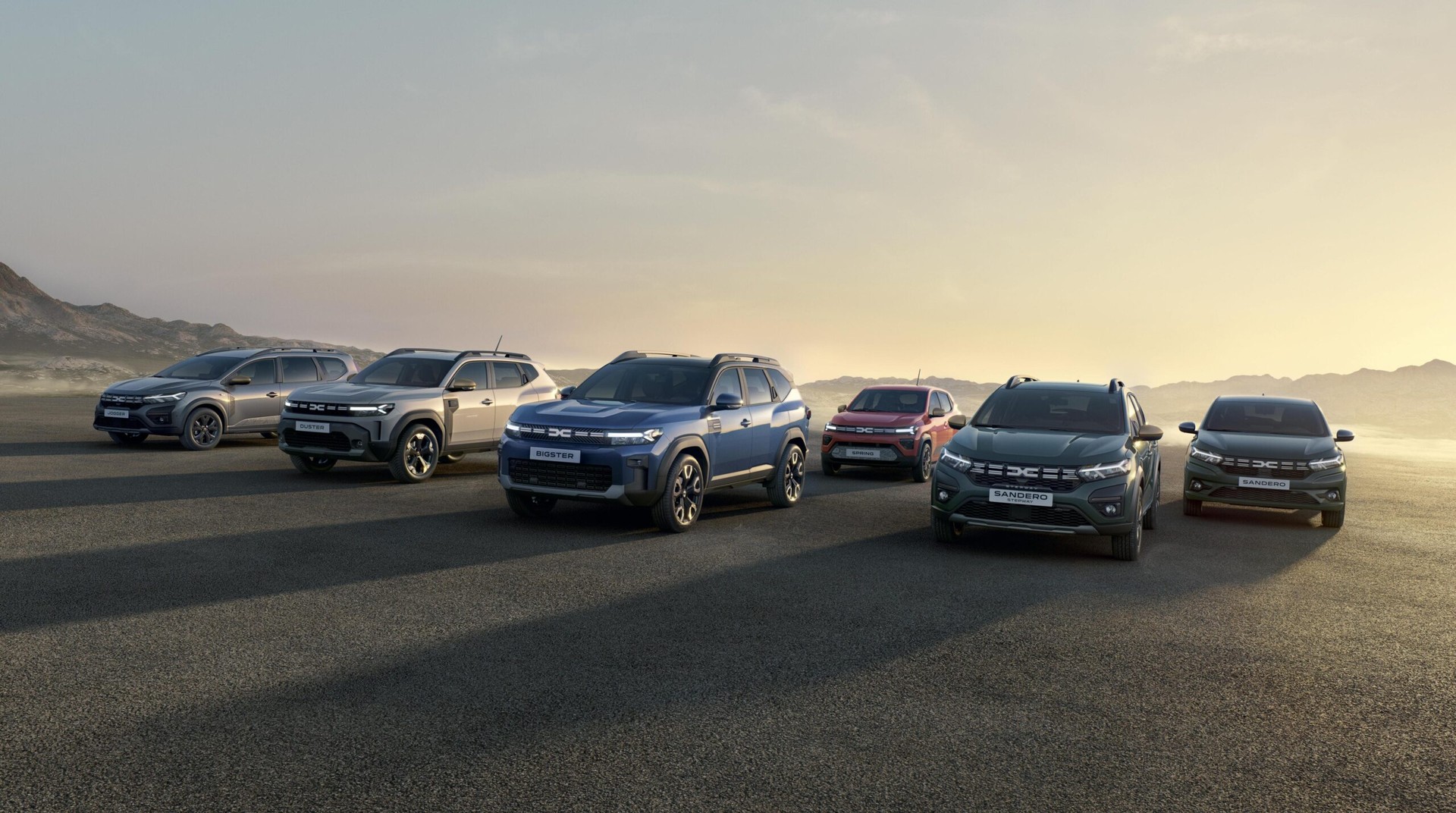 The Dacia 2024 lineup showcases a diverse range of models, including the Sandero, Bigster, and Duster, set against a scenic backdrop. (Photo via press.dacia.co.uk)