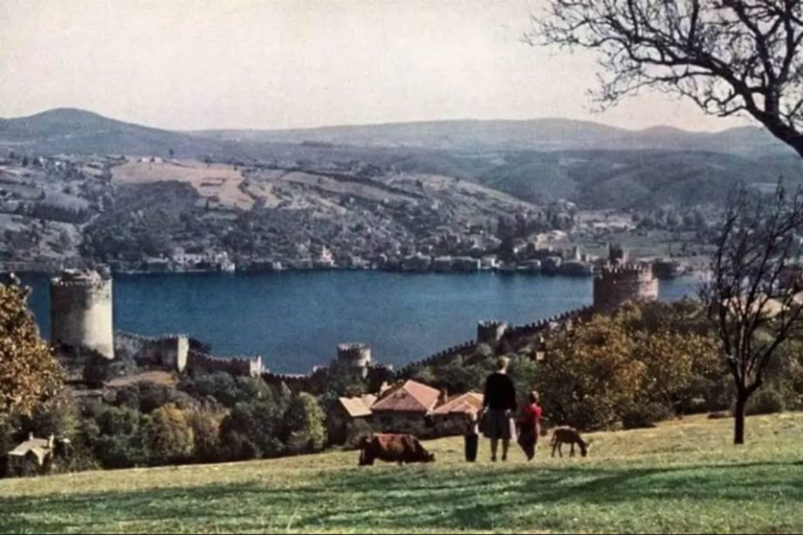 A blonde woman and two children stroll down a grassy hill toward Rumeli Hisari, the photo capturing a serene and untouched Istanbul nearly 100 years ago, Istanbul, Türkiye, Sept. 3, 2024. (Photo via Instagram / @kaybolantarihinpesinde)