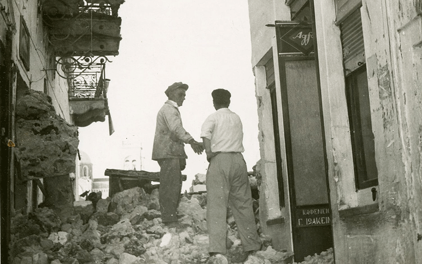Two men stand on a pile of rubble in Fira, the main town of Santorini, following the devastating earthquake of July 1956. (Photo via Santorini Archive Project)