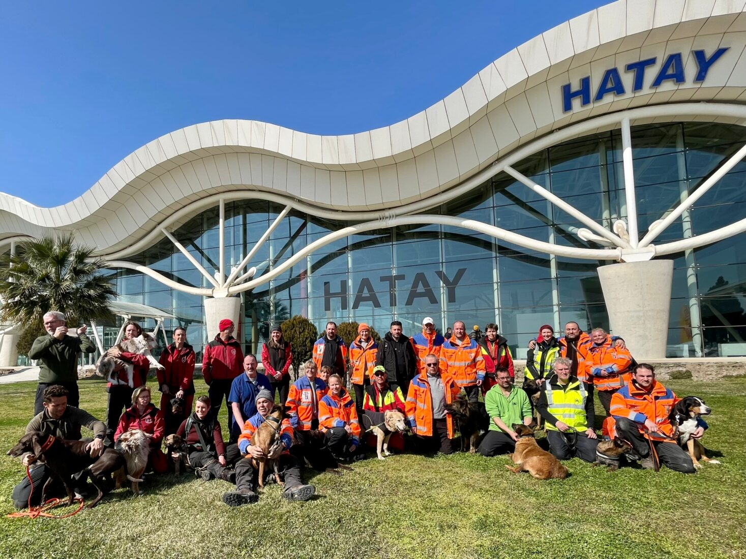 Dutch and Turkish search-and-rescue volunteers gather with their trained dogs outside Hatay Airport for a photo before saying goodbye, Türkiye, February 2023. (Courtesy of SAR)