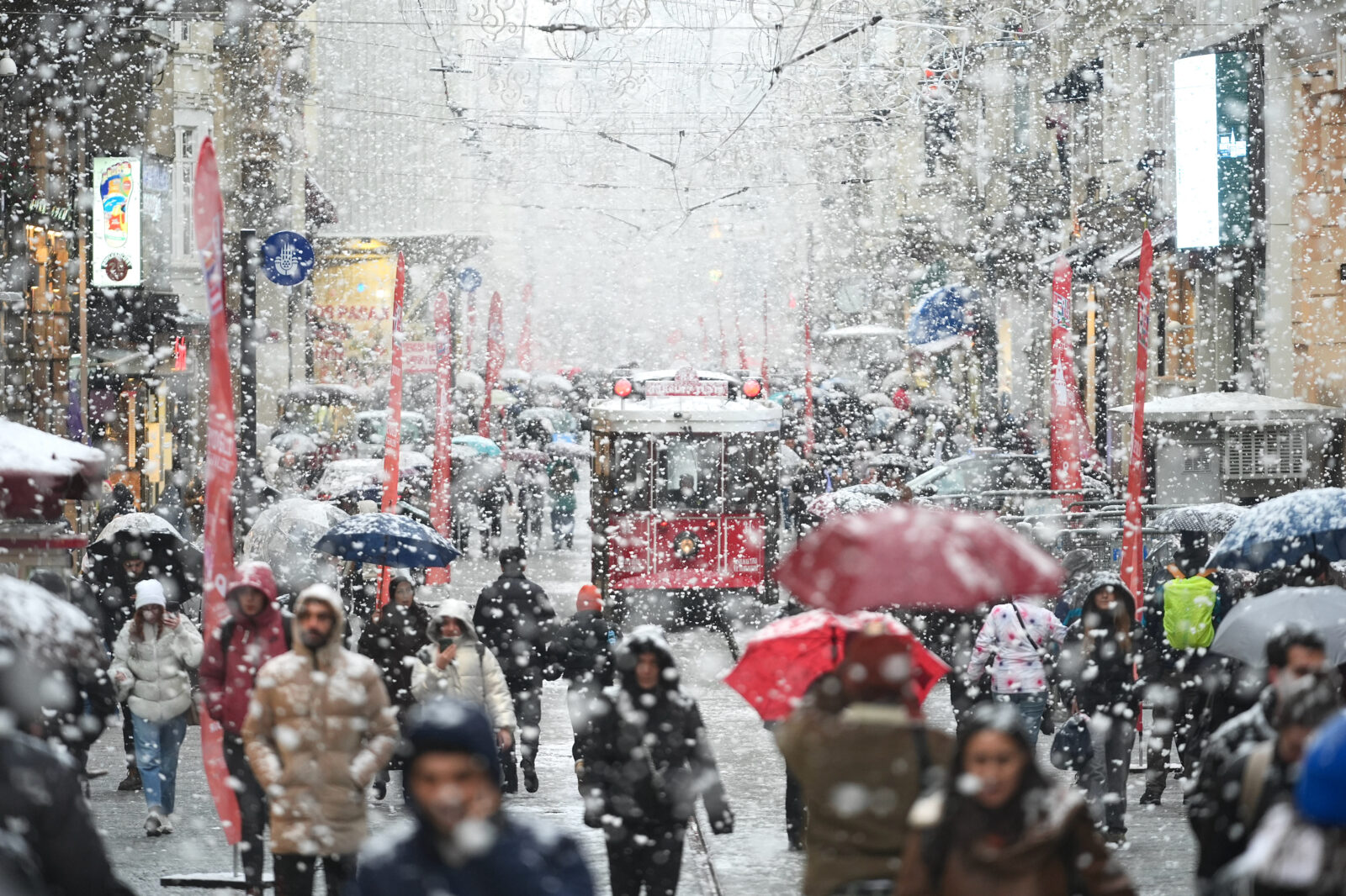 People walk with umbrellas on Istiklal Street as the nostalgic tram operates during a snowstorm in Taksim, Beyoglu district, Istanbul, Türkiye, Feb. 19, 2025. (AA Photo)