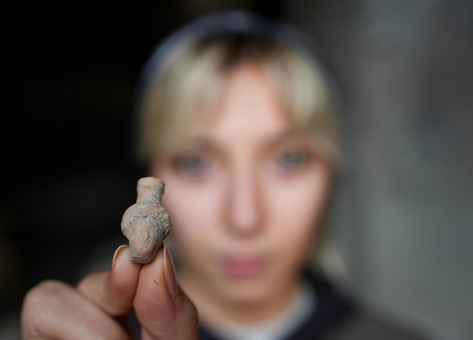 A female archaeologist shows a small artifact found in the 