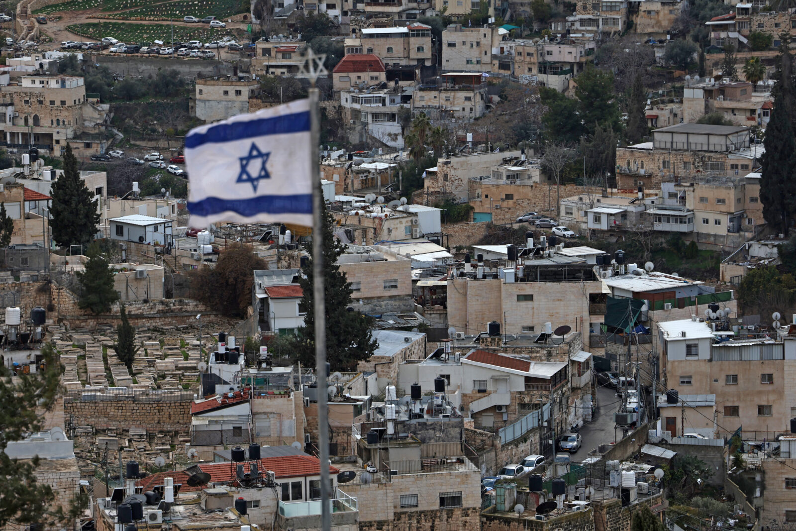 An Israeli flag sways in the wind atop a building over east Jerusalem's Arab neighbourhood of al-Tur on February 7, 2025. (AFP Photo)