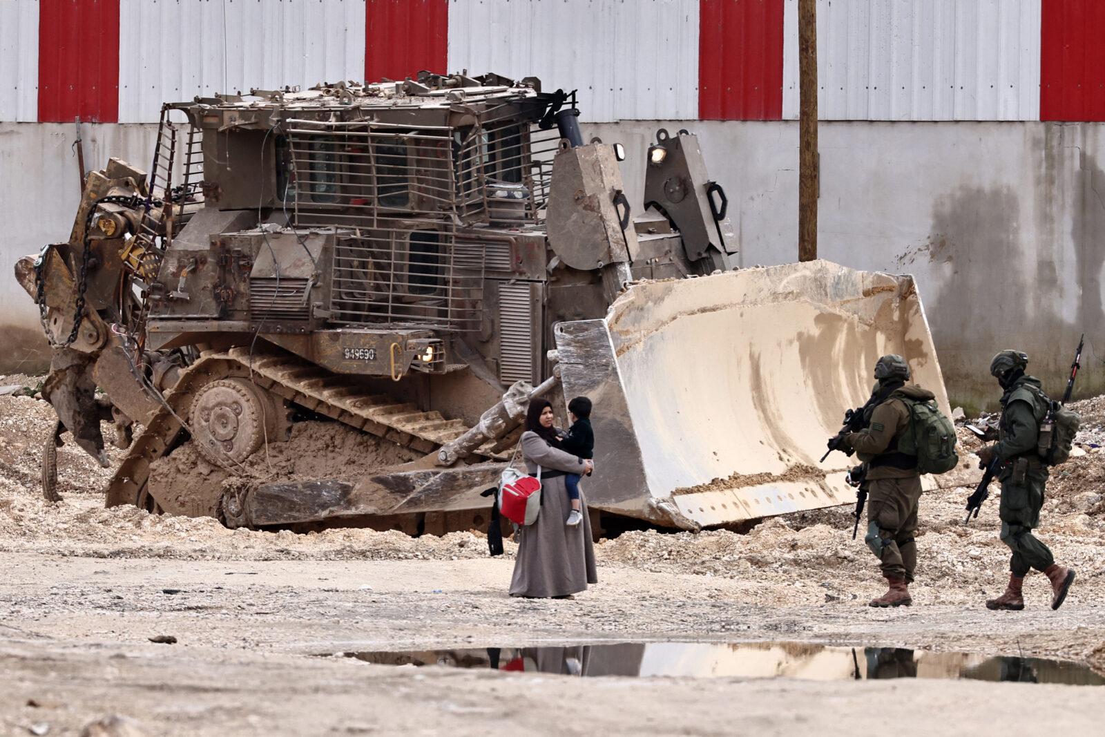 Israeli soldiers speak with a Palestinian woman as she leaves her home for safety during a raid by the army in the Nur Shams refugee camp near Tulkarem in the occupied West Bank, Feb. 11, 2025. (AFP Photo)