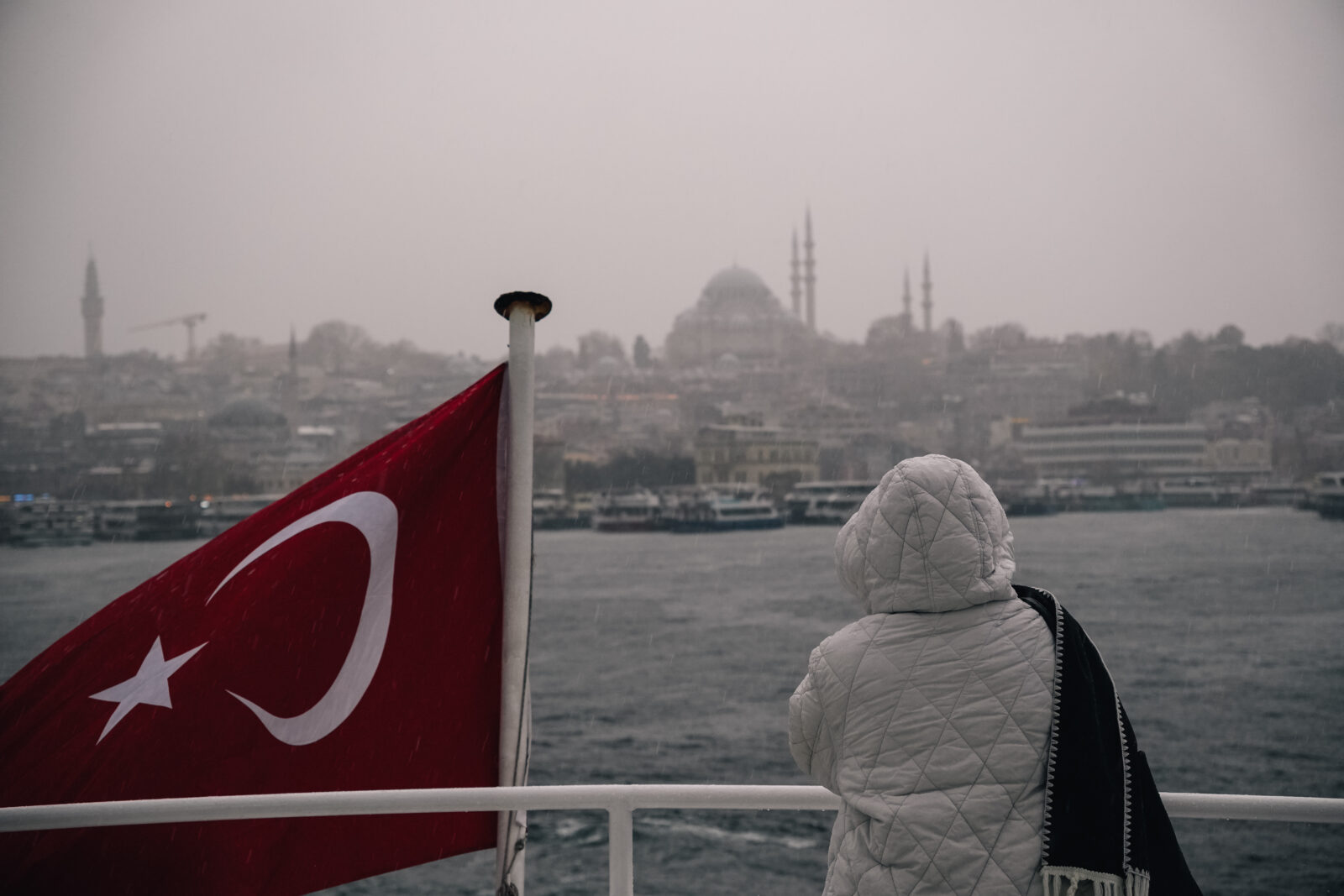 A tourist stands on a ferry deck in Istanbul, gazing at the stormy skyline. (Adobe Stock Photo)
