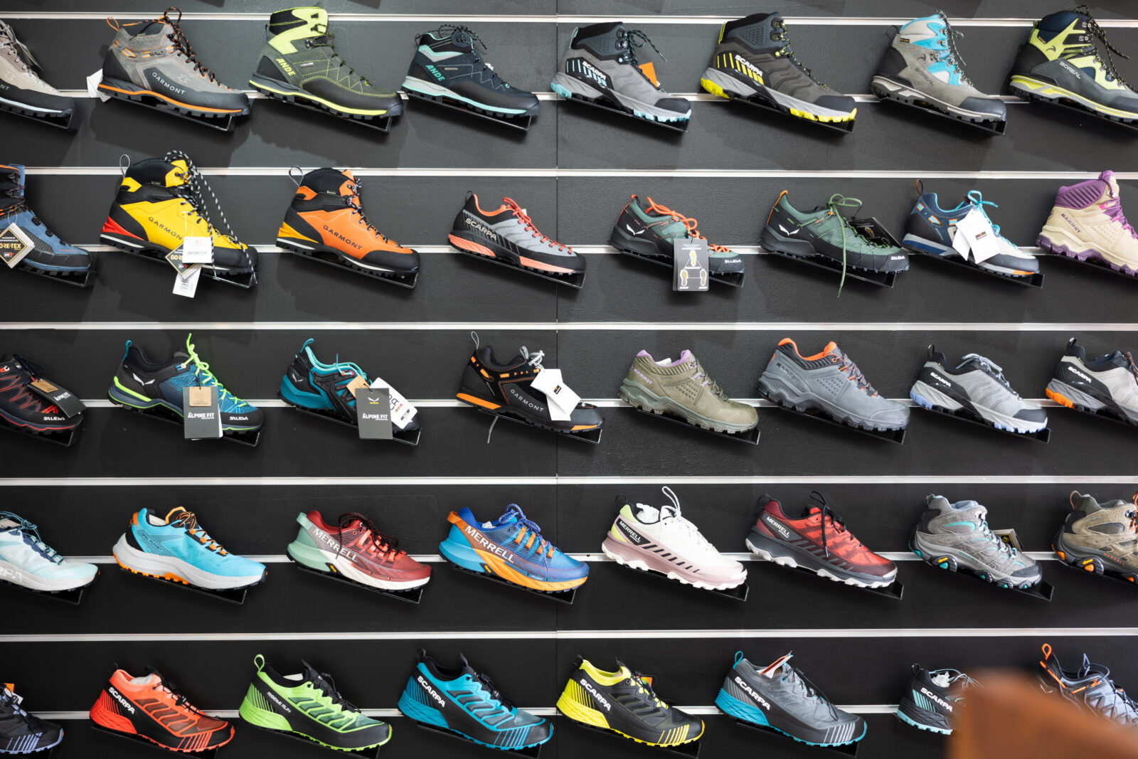 A retail display of various hiking and trail running shoes from different brands, including Merrell, Garmont, and Scarpa. (Adobe Stock Photo)