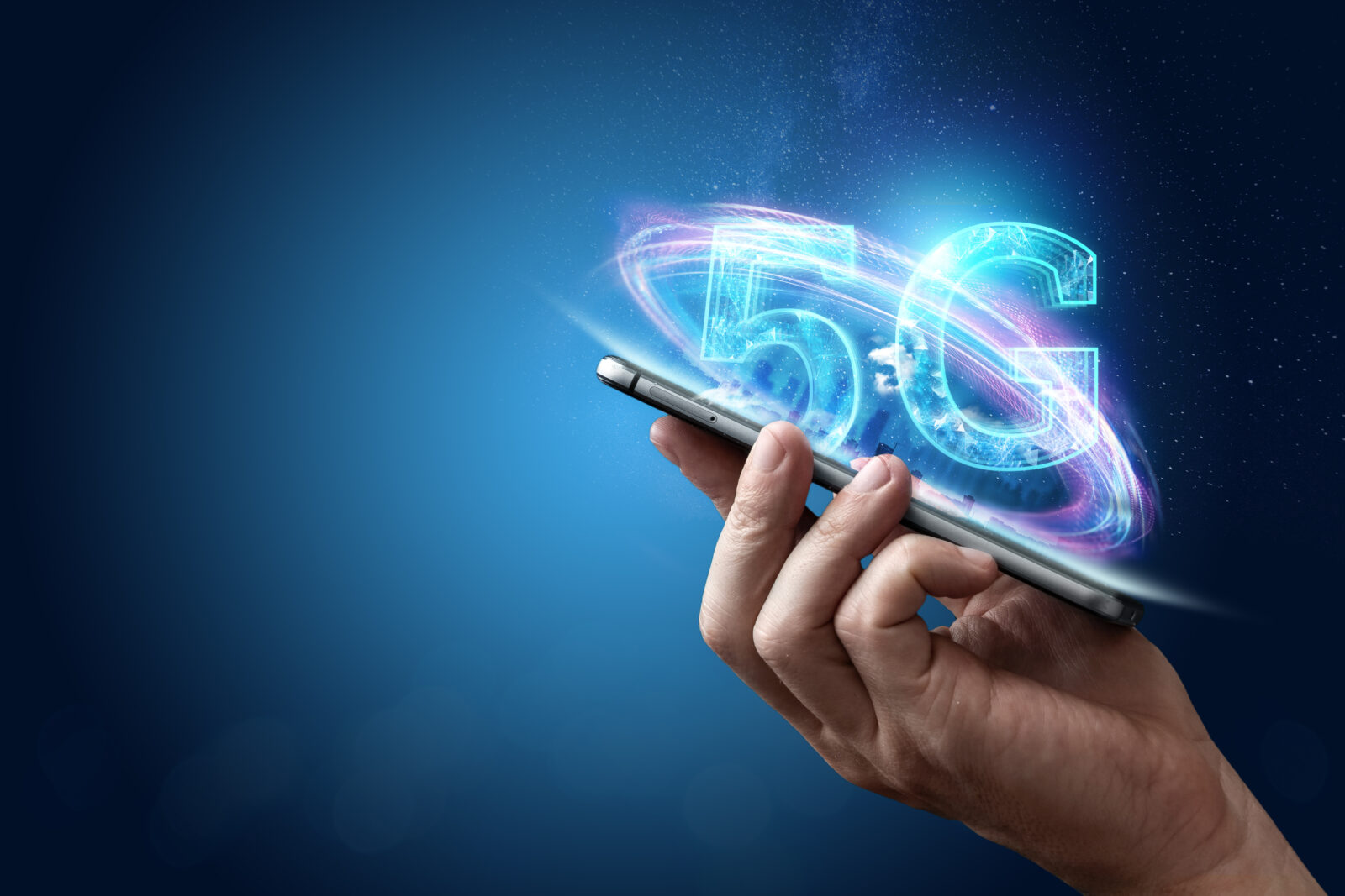A person holding a phone with a 5G hologram in the background of the city. (Adobe Stock Photo)