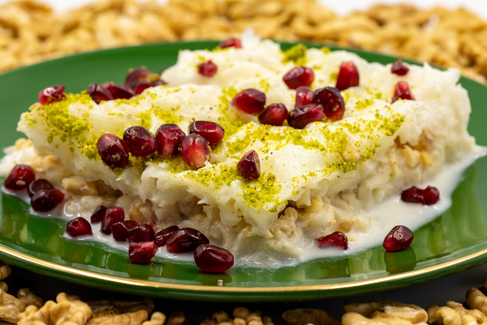 Close-up of Gullac, a Turkish dessert made with milk-soaked pastry layers, walnuts, and garnished with pomegranate seeds and crushed pistachios, usually enjoyed during Ramadan in Türkiye. (Adobe Stock Photo)