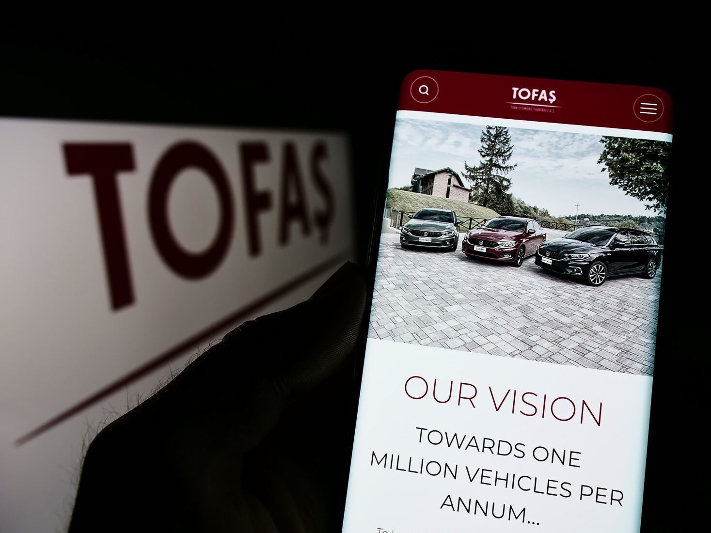 The photo illustration shows a person holding a smartphone displaying the TOFAS official website in Germany on November 6, 2022. (Adobe Stock Photo)