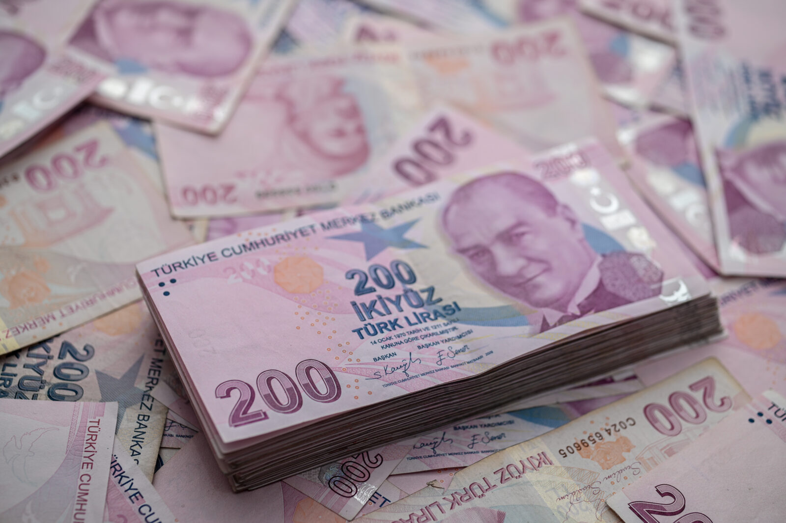 File photo shows a stack of 200 Turkish lira banknotes is displayed on a scattered pile of various Turkish lira denominations. (Adobe Stock Photo)