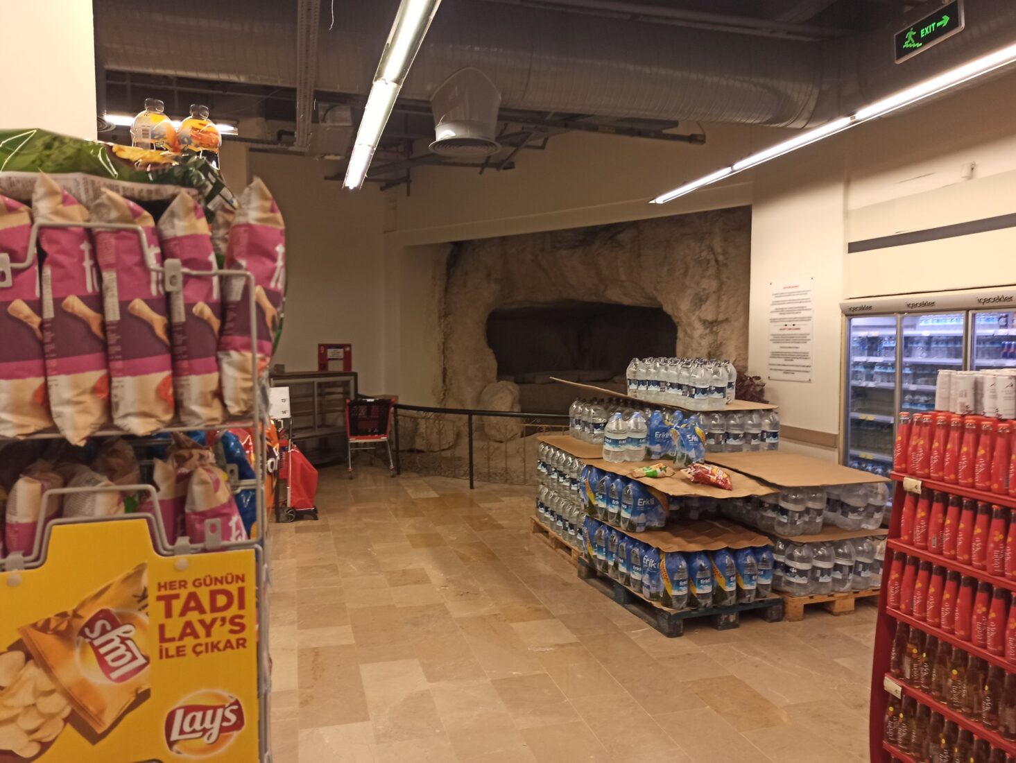 A 2,300-year-old rock-cut tomb, enclosed by barriers, is displayed inside a supermarket. (Photo via X)