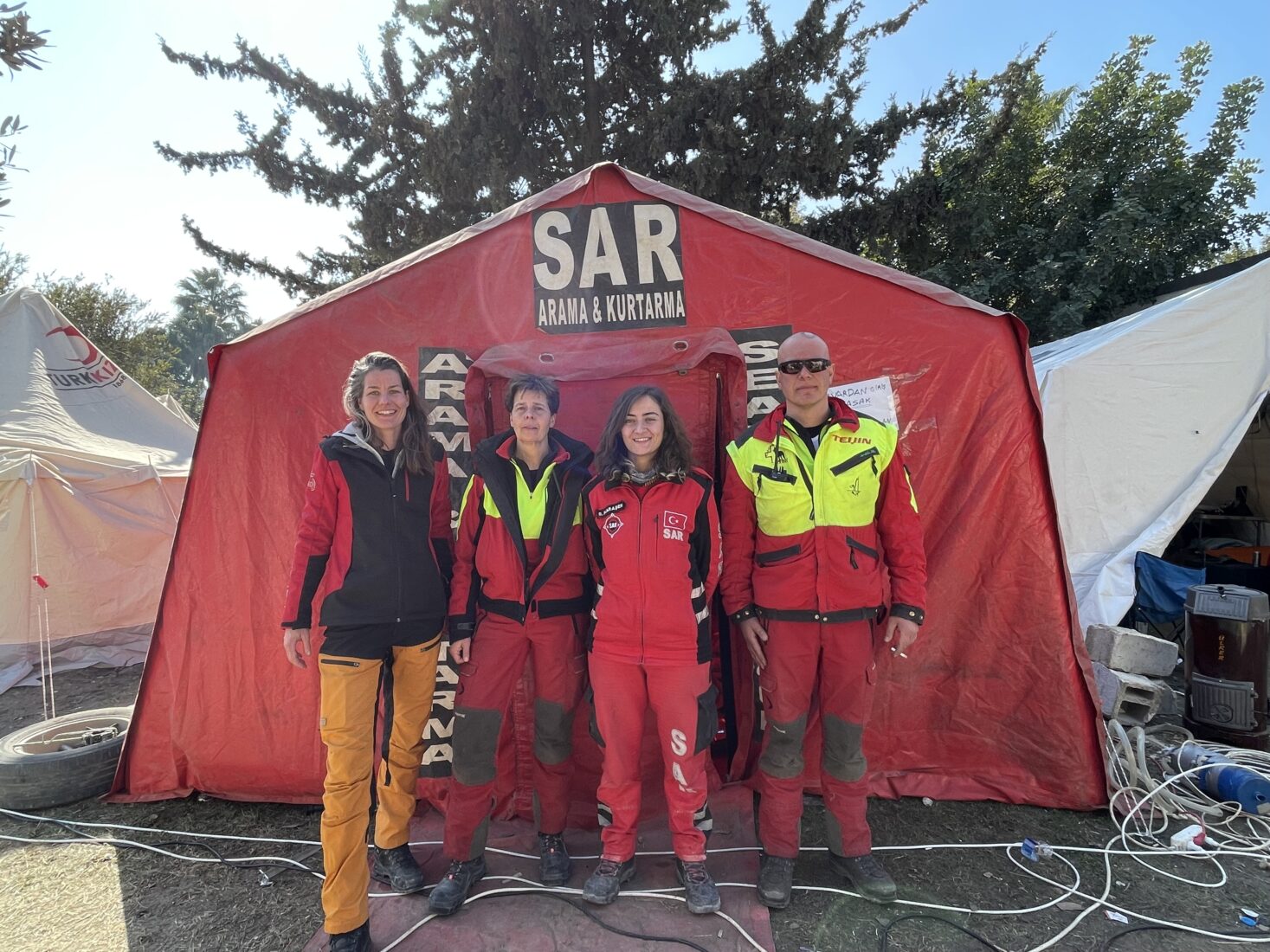 SAR volunteer Basak Karasen and Dutch volunteers stand together at their base camp after days of rescue operations, Antakya, Türkiye, Feb. 2023. (Courtesy of SAR)