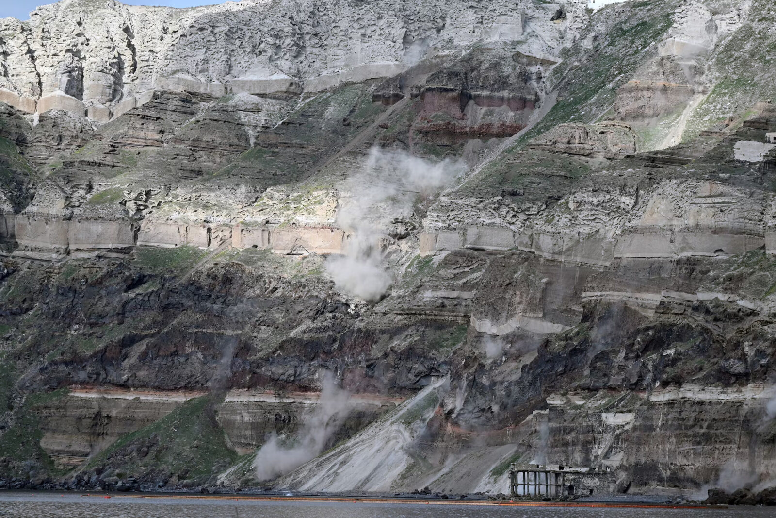Dust rises following a landslide triggered by high seismic activity on the island of Santorini, Feb. 3. In recent days, hundreds of earthquakes have been recorded every few minutes in the sea between the volcanic islands of Santorini and Amorgos in the Aegean Sea. (Photo via Chinese Daily)