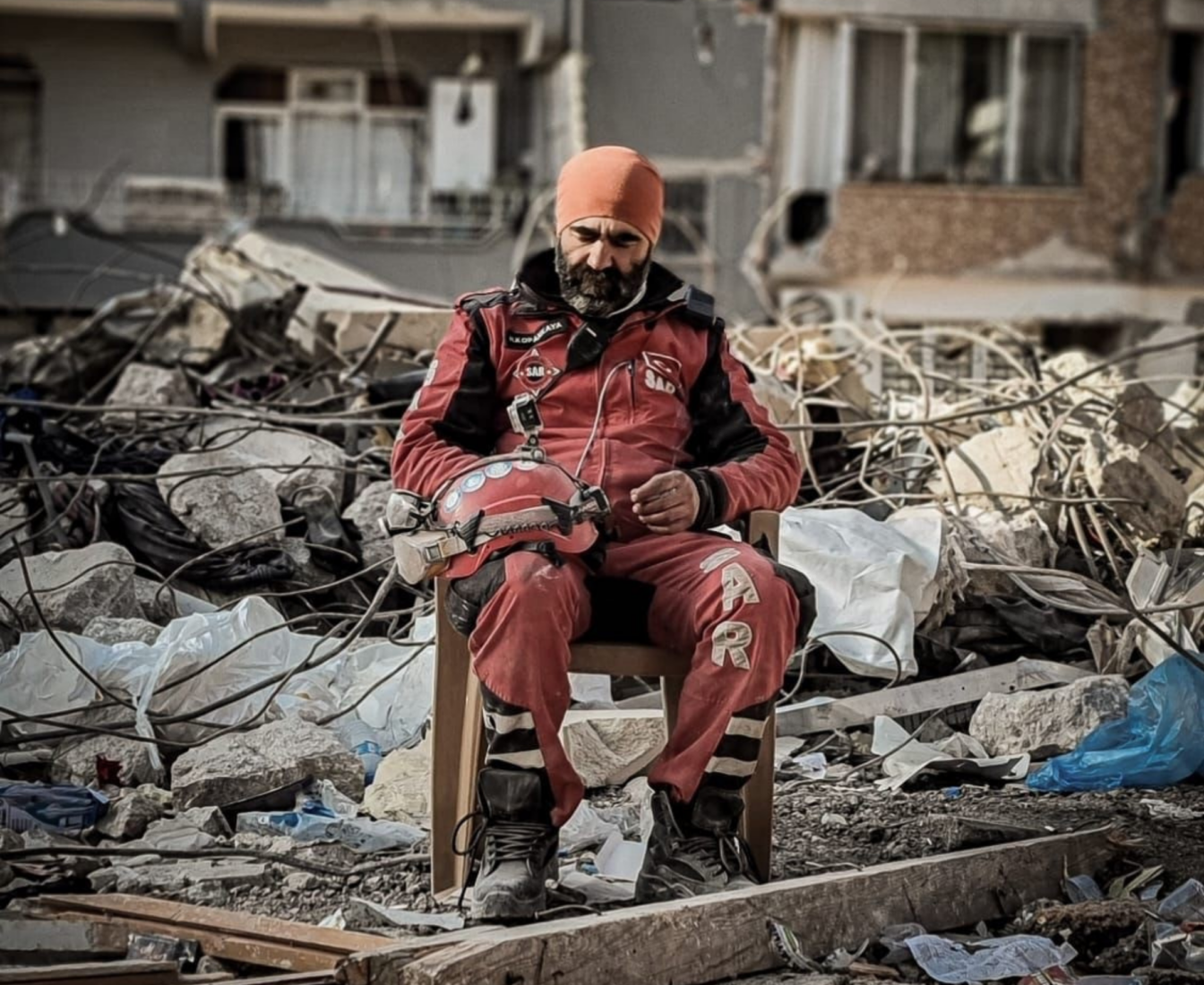 A SAR volunteer in Antakya takes a moment to rest amid the destruction left by the 2023 earthquakes, Türkiye, February 2023. (Courtesy of SAR)