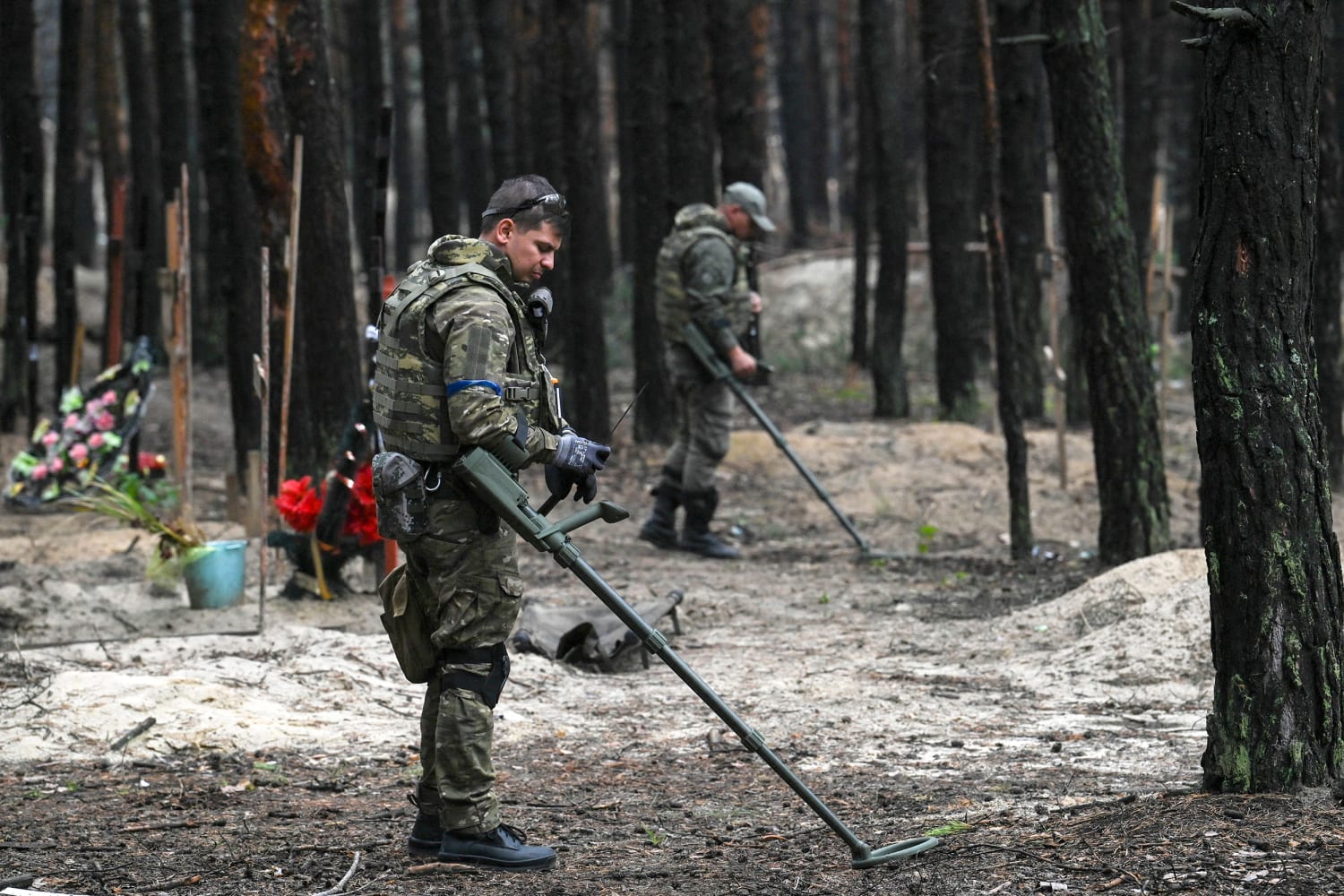 Ukrainian servicemen search for land mines at a burial site in a forest on the outskirts of Izyum, eastern Ukraine, in 2022 (AFP Photo) 