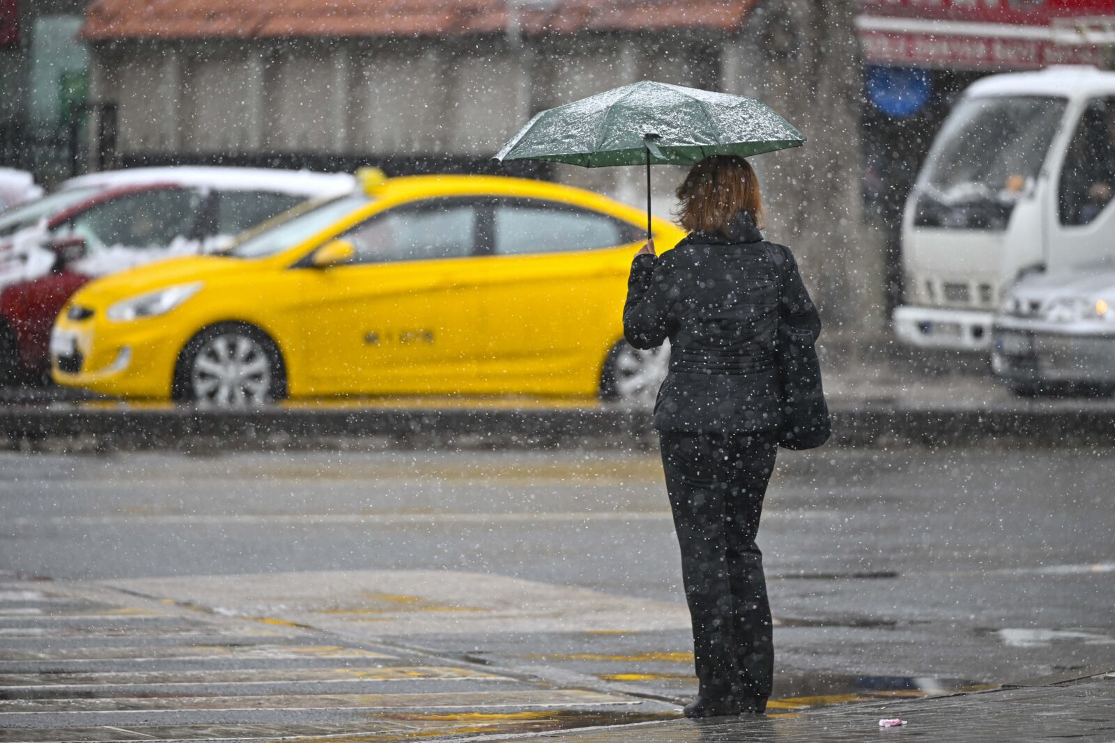 A woman, with an umbrella, walks during the snowfall in Ankara, Türkiye, March 19, 2025. (AA Photo)