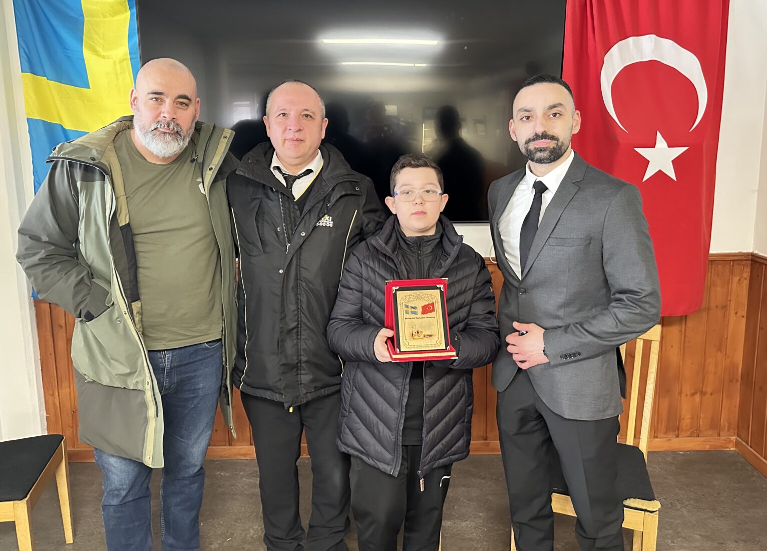 Ugur Ergun (R), President of the Stockholm Botkyrka Turkish Cultural Association, presented a plaque to Mesut Zengin and his 14-year-old son, Furkan Zengin, for being role models in Stockholm, Sweden, March 31, 2025. (AA Photo)