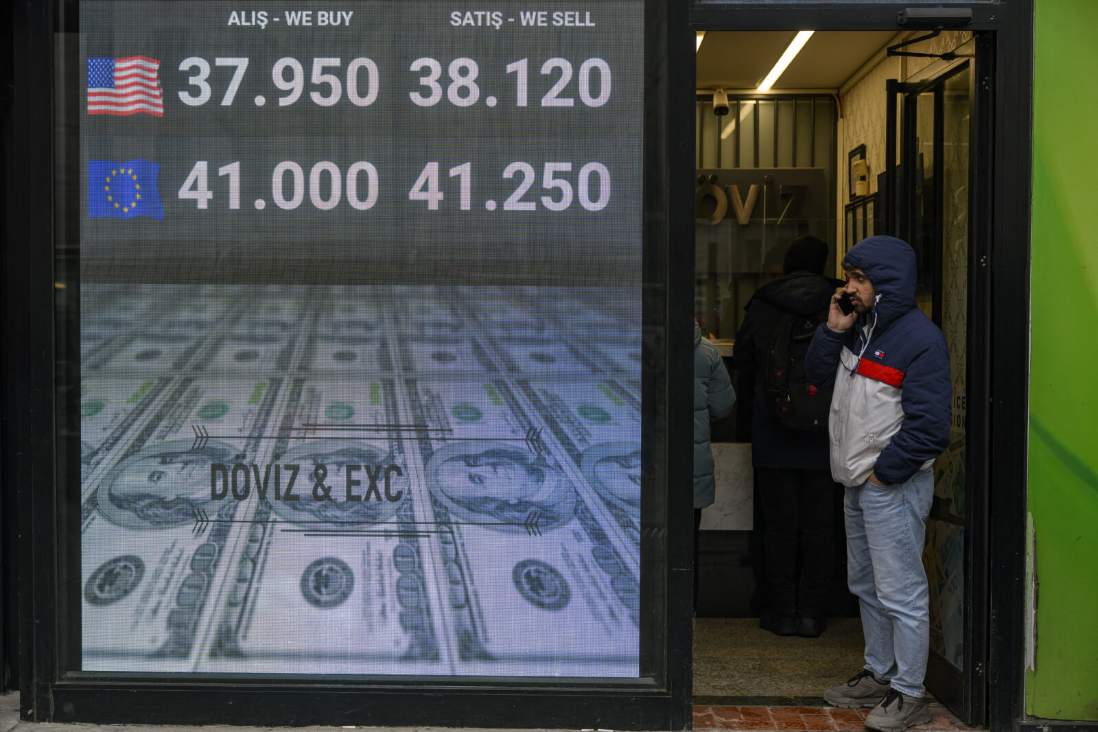 A man calls with his smartphone as he stands next to a currency exchange board showing the Turkish Lira, which fell to historic lows against the dollar, a day after the arrest of Istanbul's Mayor Ekrem Imamoglu in Istanbul, Türkiye on March 20, 2025. (AFP Photo)