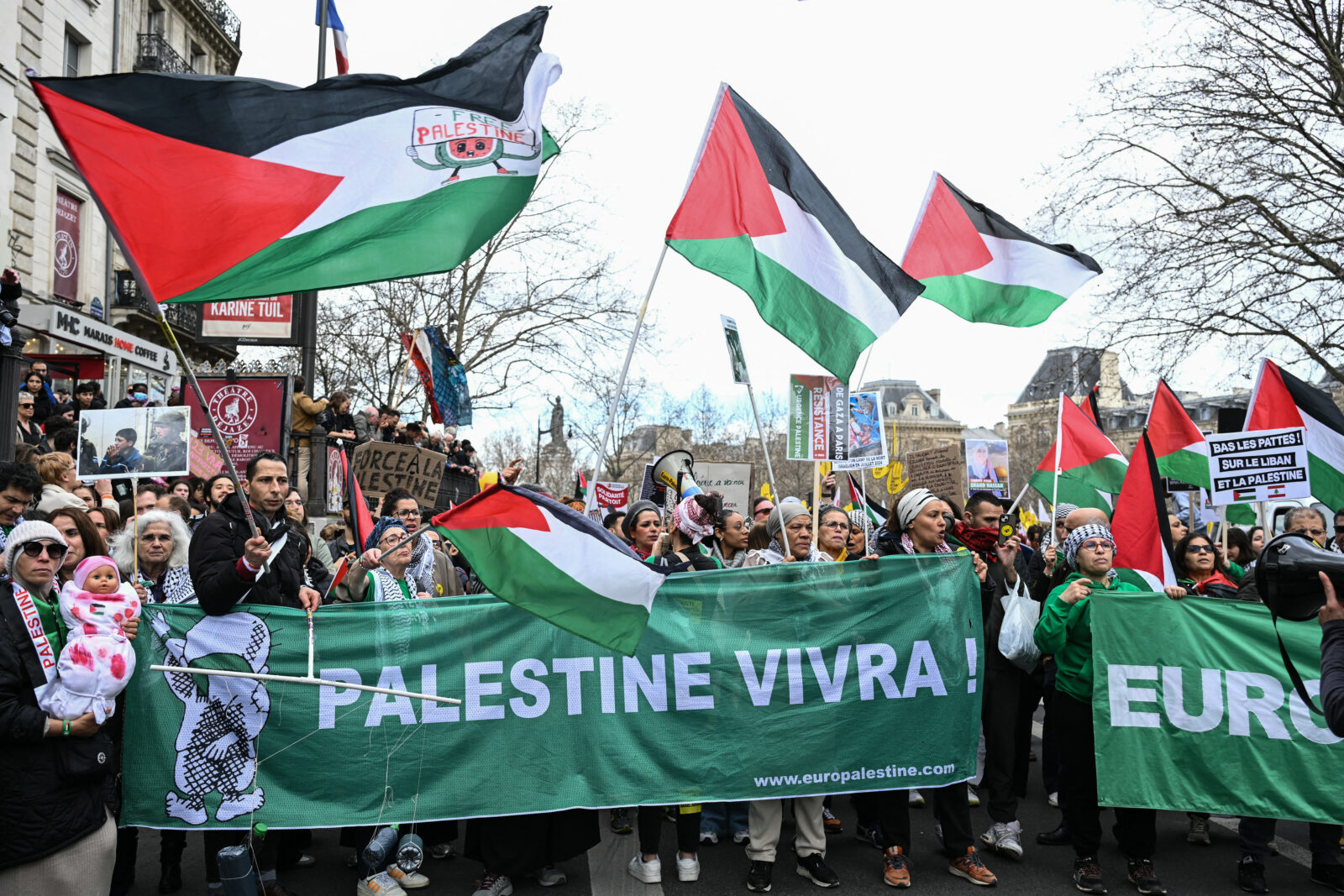 Protestors wave Palestinian flags and hold a banner reading 