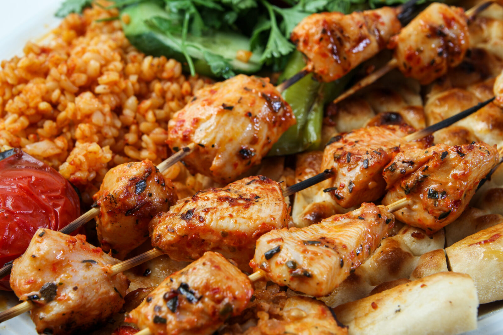 Juicy and flavorful Turkish grilled chicken skewers served with bulgur pilaf, roasted vegetables, and warm flatbread. (Adobe Stock Photo)
