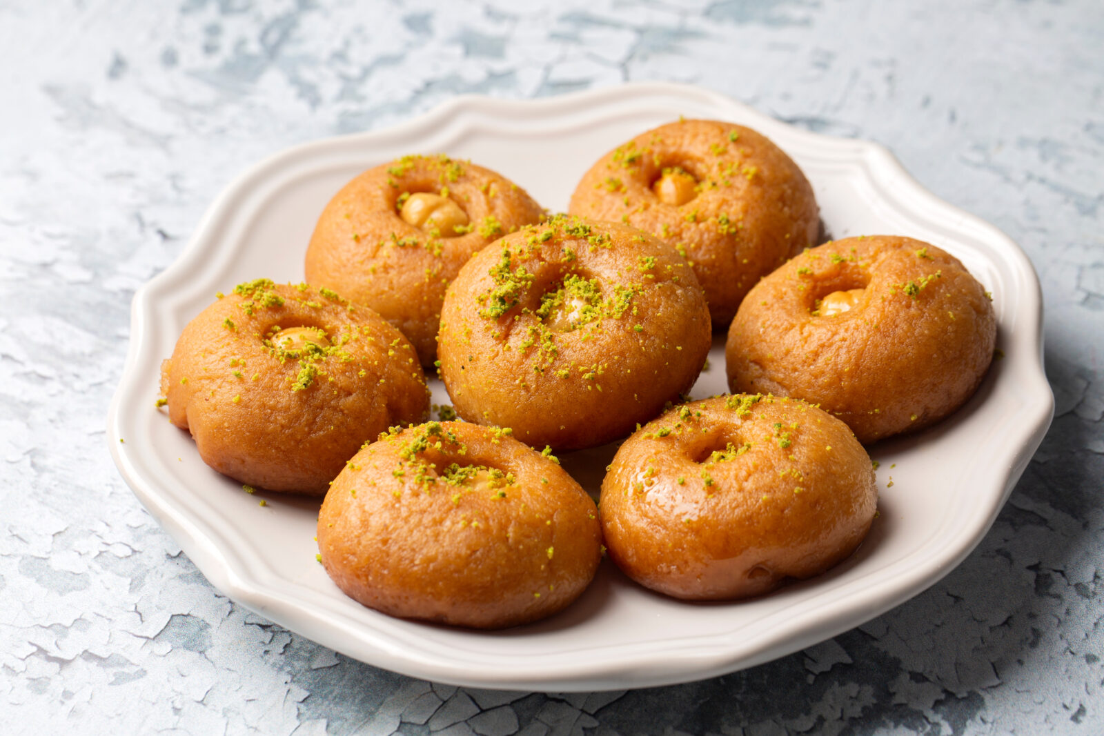 Sekerpare, traditional Turkish semolina cookies soaked in sweet syrup and garnished with crushed pistachios, is a popular dessert for iftar and festive occasions. (Adobe Stock Photo)